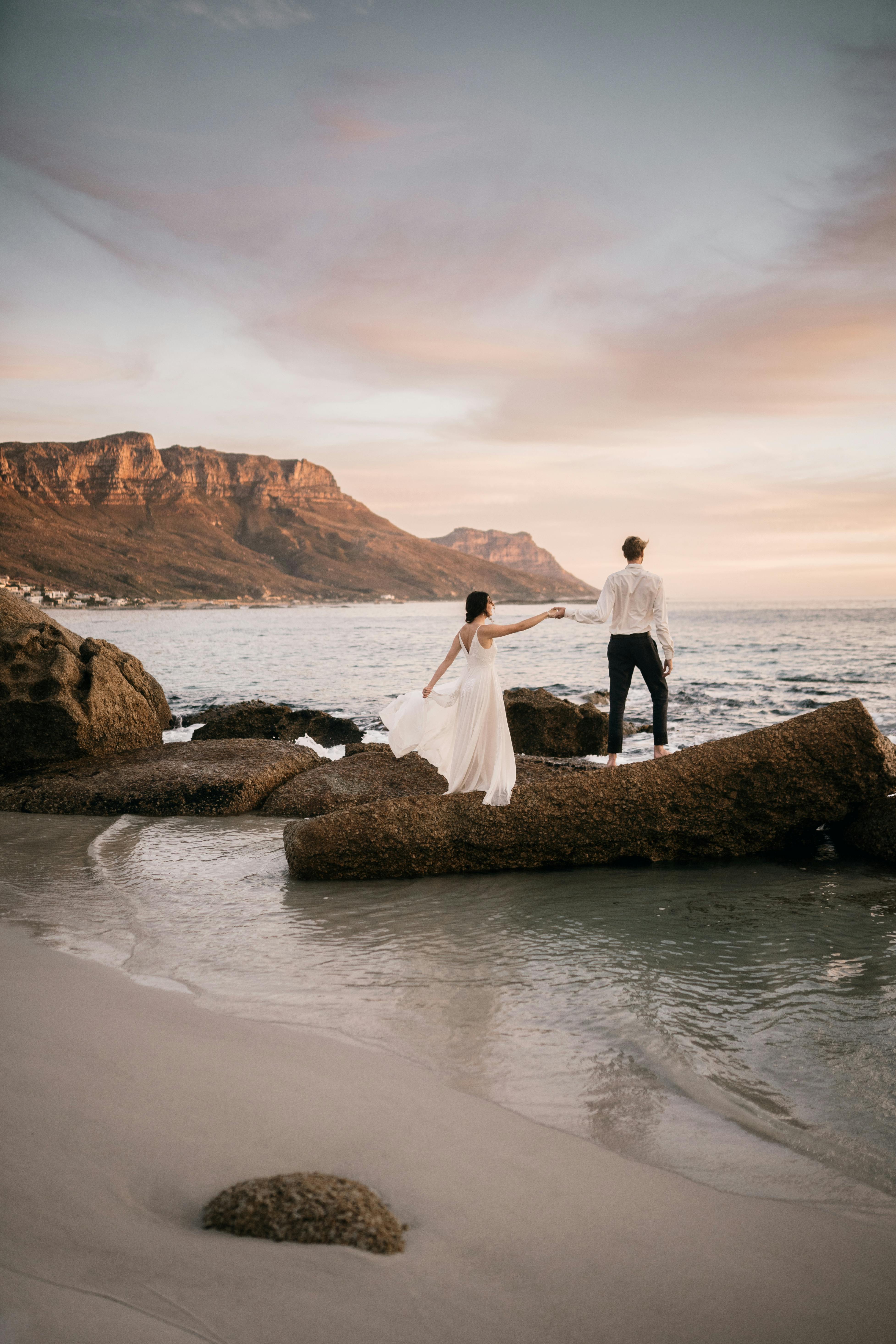 photo of the couple sitting on a rock at the beach